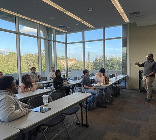 Students at tables in Student Center listening to instructor.