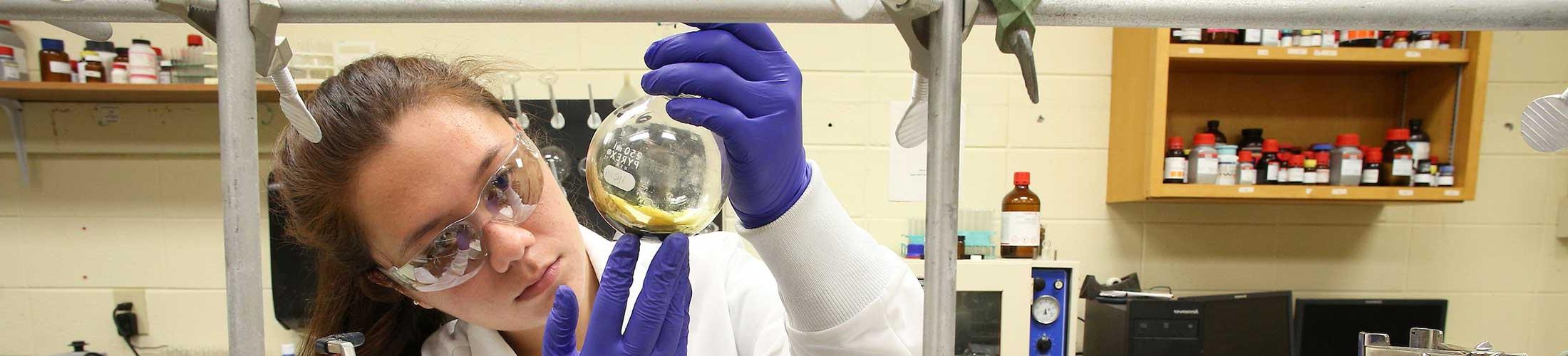 Student working in lab holding a beaker.